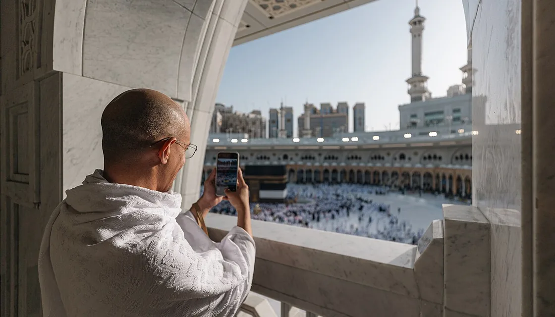 حاج يستخدم هاتفه المحمول أمام المسجد الحرام في مكة
